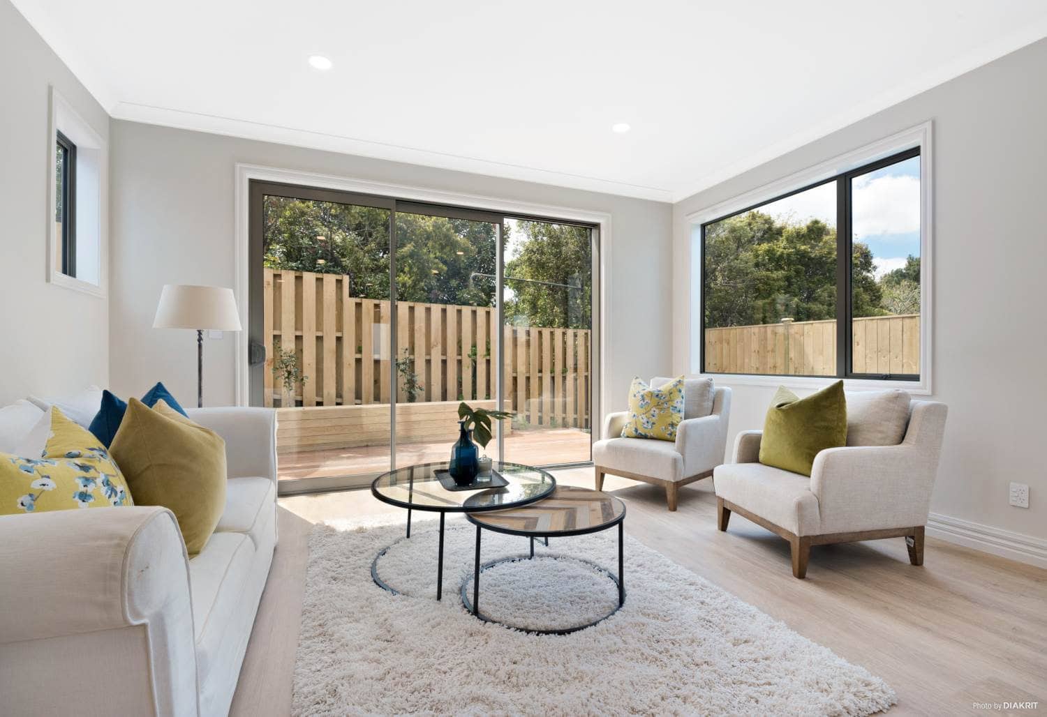 Living room with a sofa, armchairs and windows on two walls, Mairangi Bay