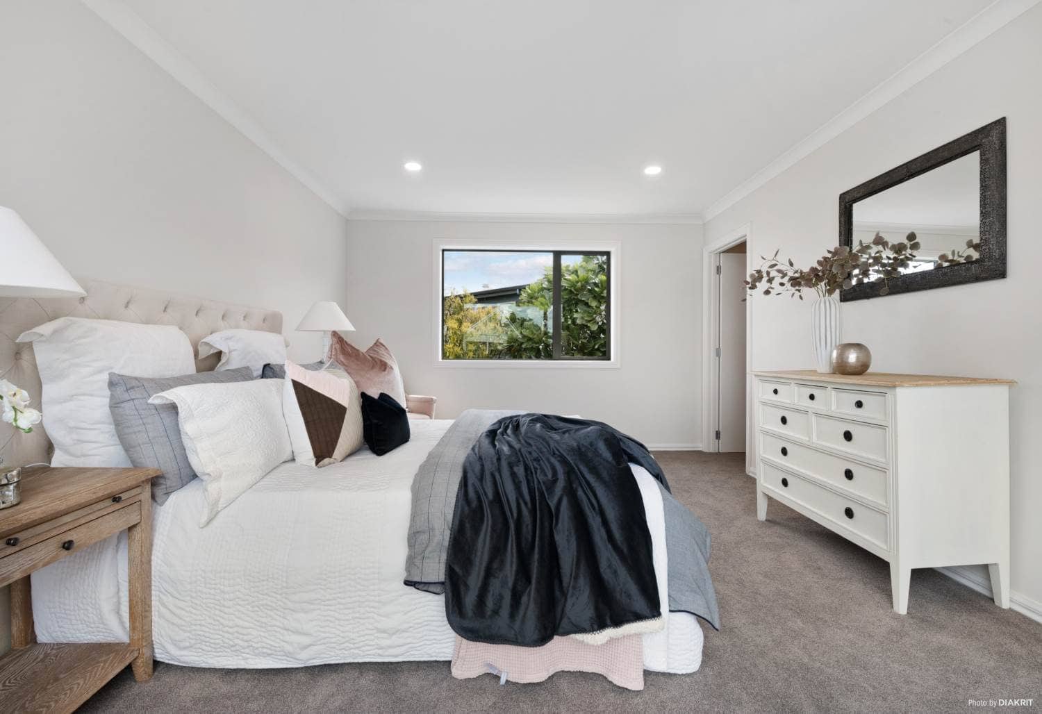 Bedroom with a dresser, mirror and a high window, Mairangi Bay