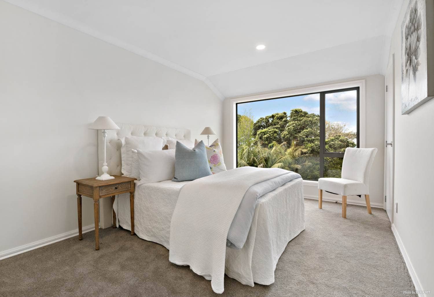 Bedroom with a wide window looking into trees, Mairangi Bay