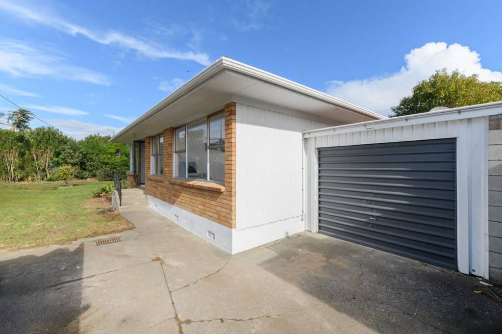 Brick and weatherboard unit with a roller-door garage before renovation, Milford