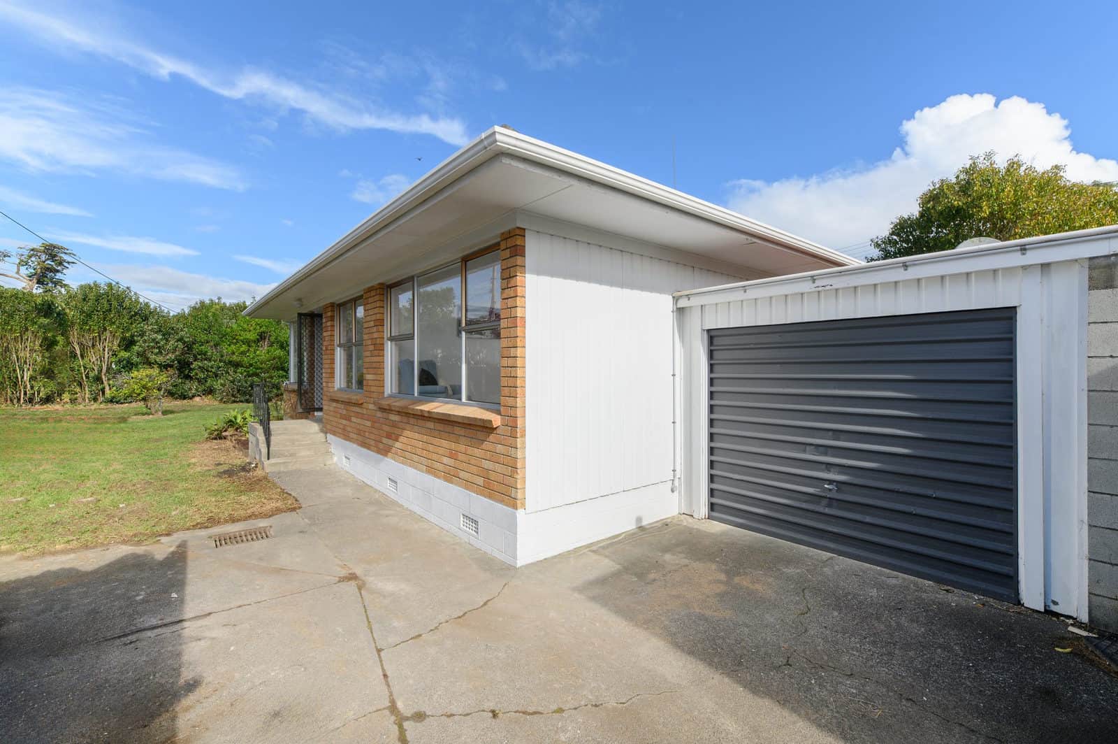 Brick and weatherboard unit with a roller-door garage before renovation, Milford
