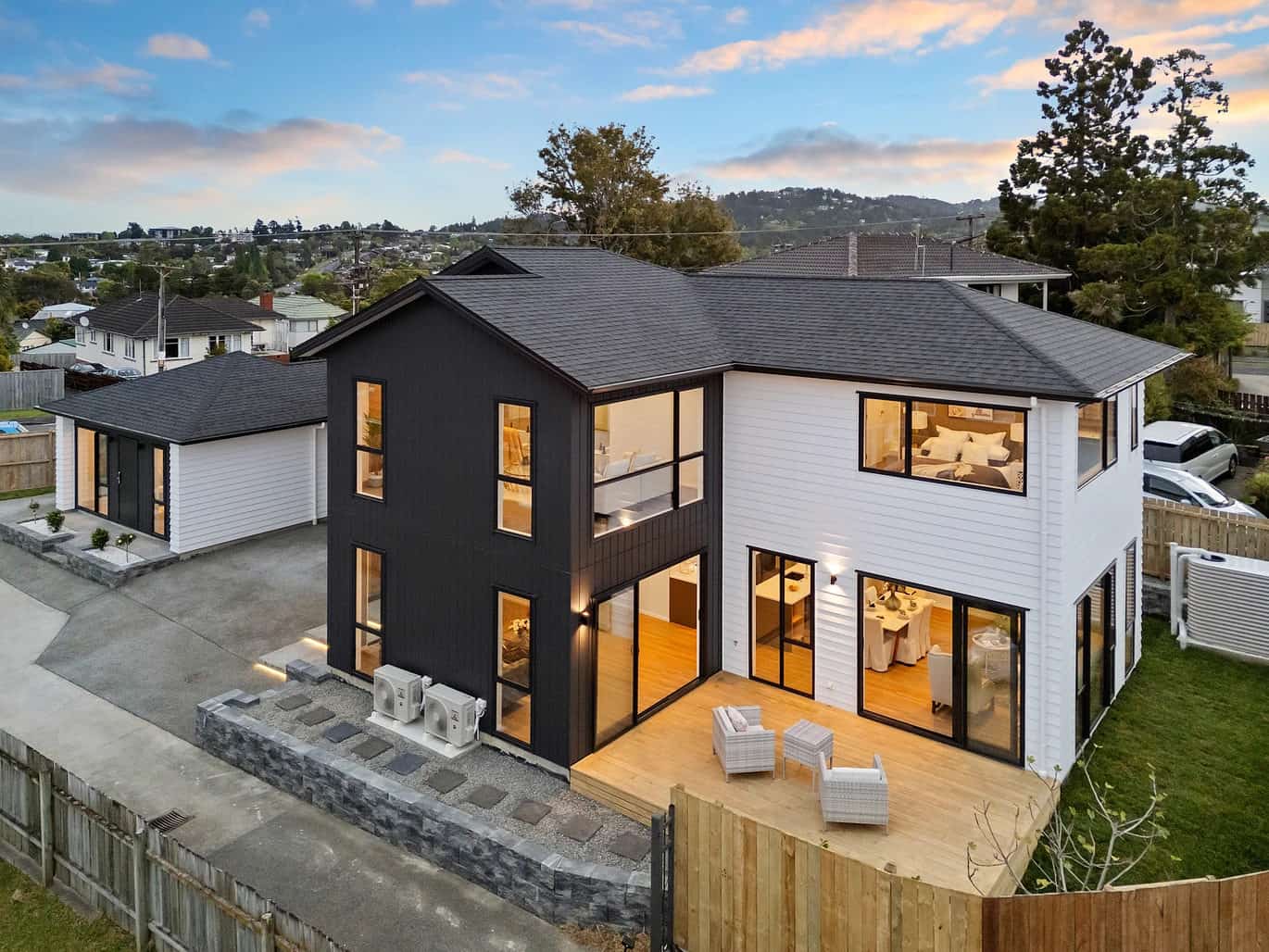 Rear of the dwellings with sliding doors onto the lawn at dusk, New Lynn