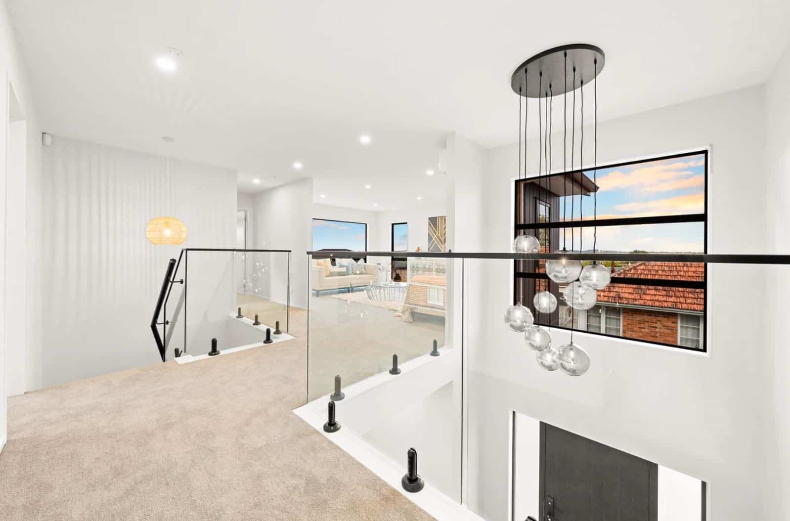 Upper landing with a glass balustrade and a cluster pendant over the void, New Lynn