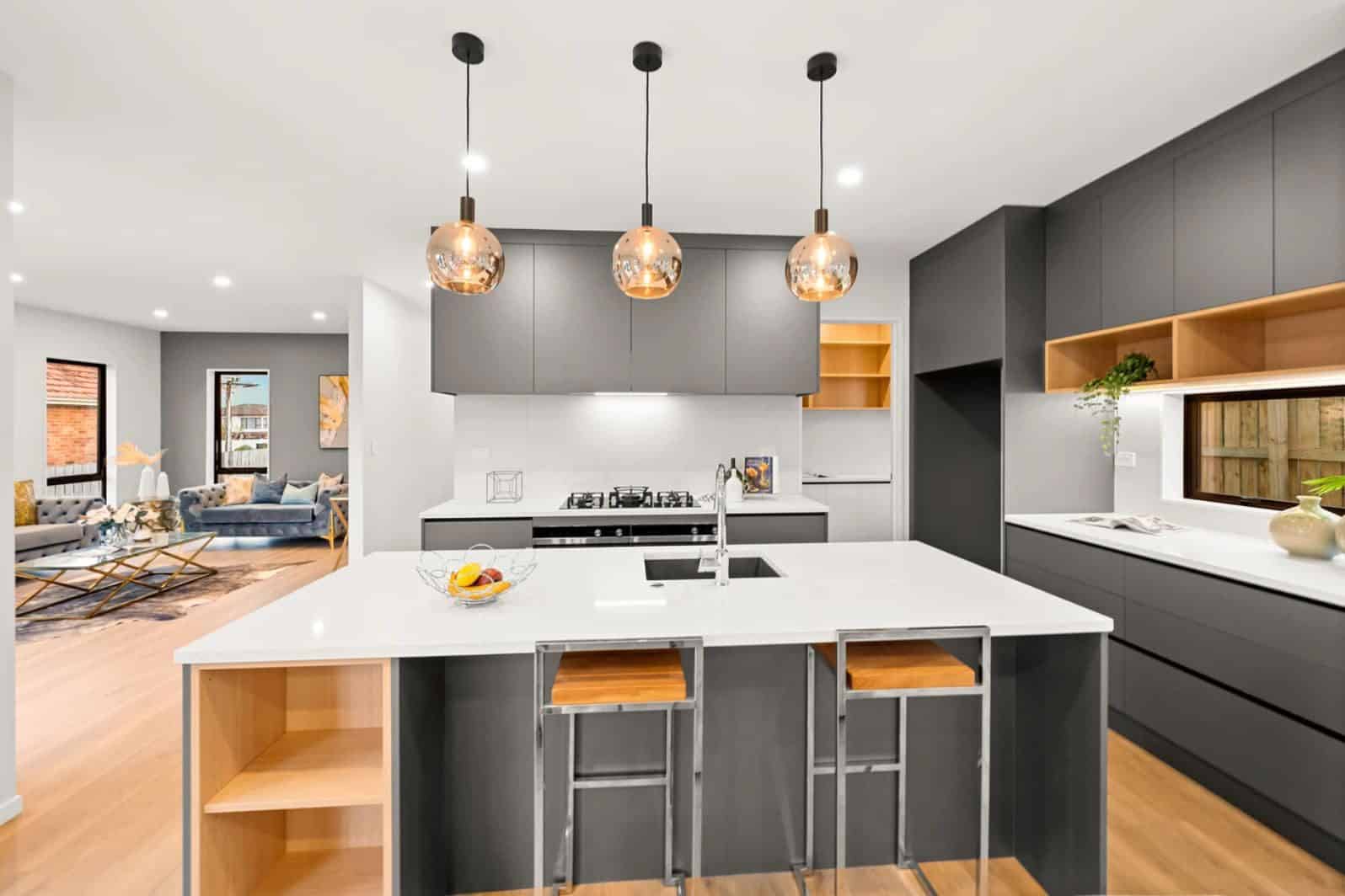 Kitchen with a grey island, timber shelving and pendant lights, New Lynn