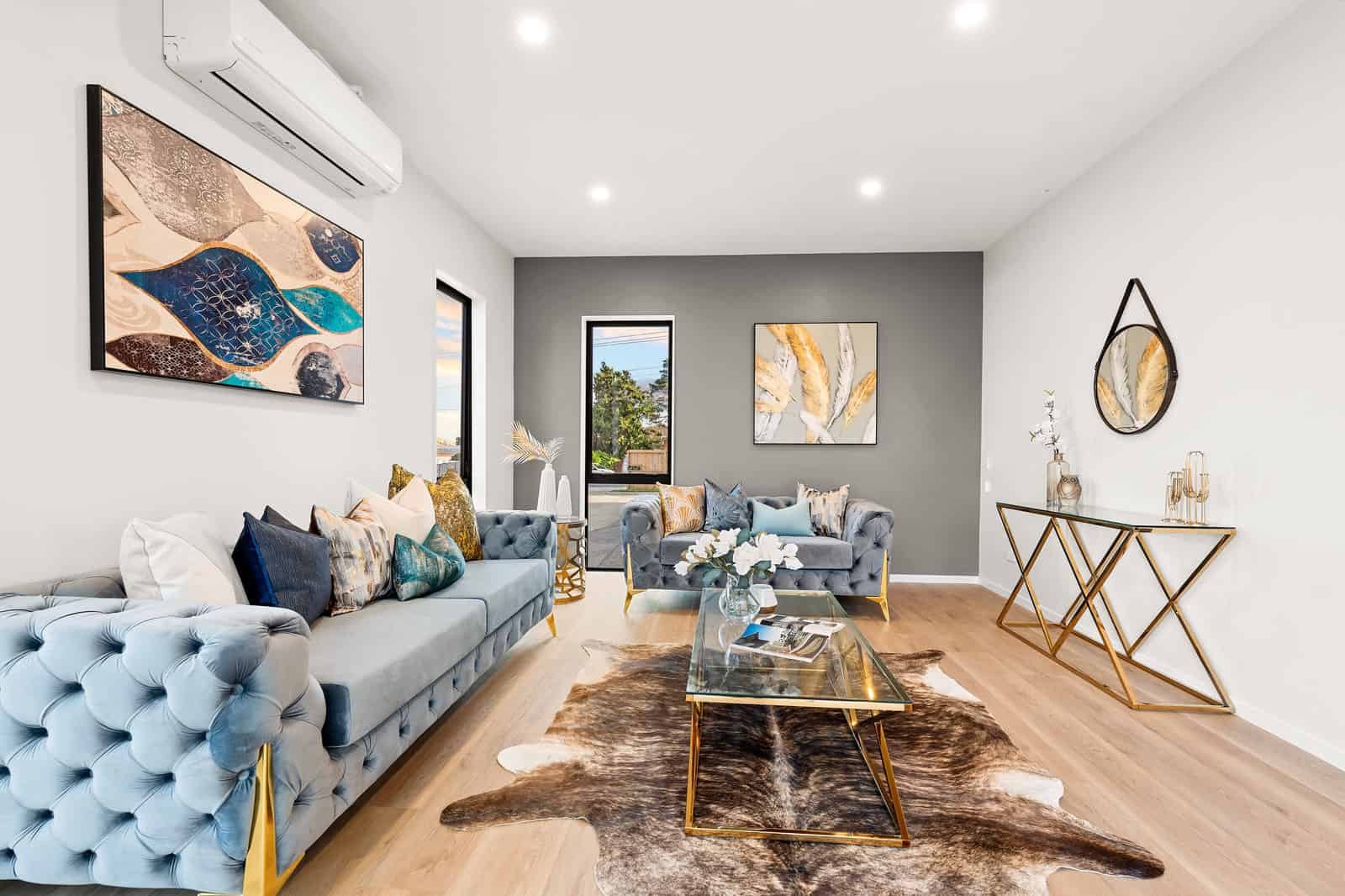 Living room with a blue velvet sofa against a grey feature wall, New Lynn