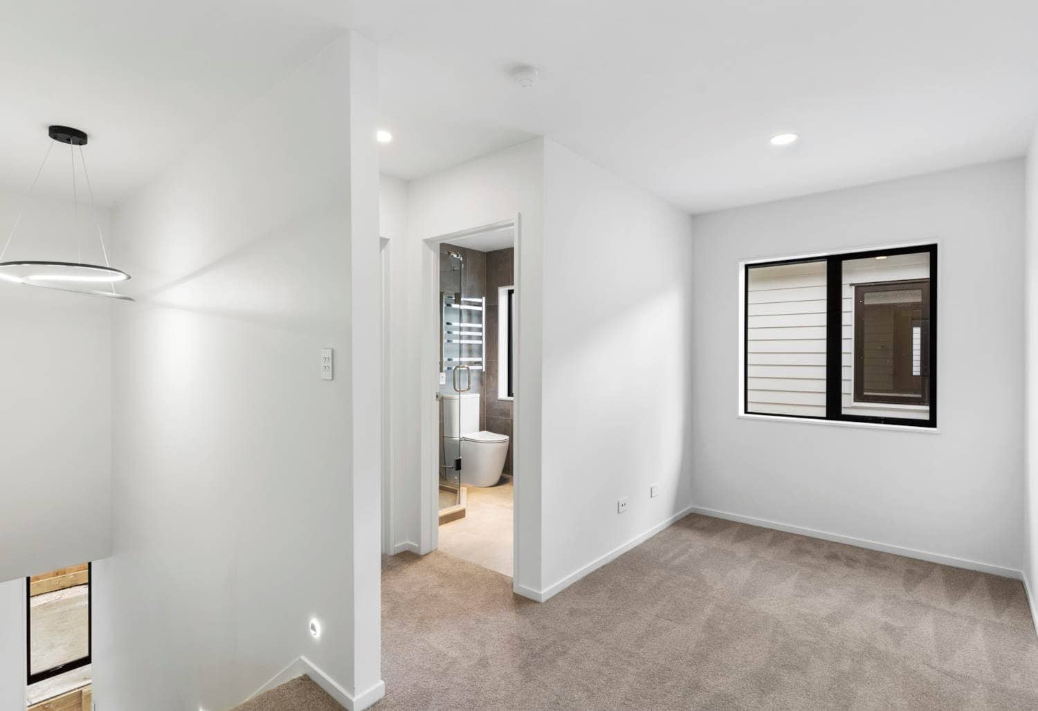 Empty room with a corner window and a bathroom through the doorway, New Lynn