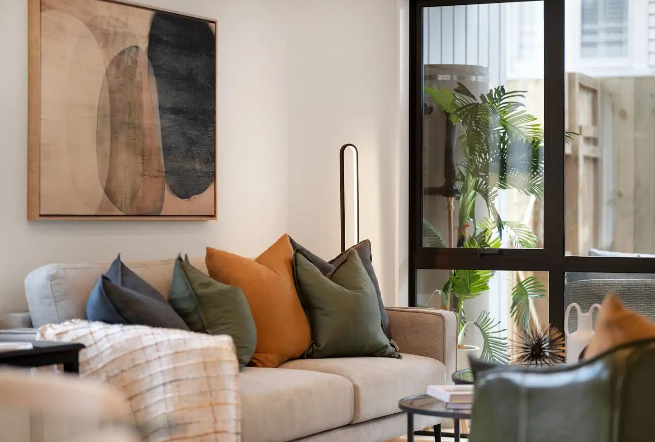 Living room with a sofa, framed artwork and glazing to a planted courtyard, New Windsor