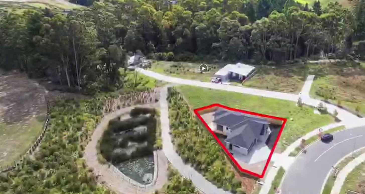 Wide aerial with the property outlined in red among bush and open ground, Orewa