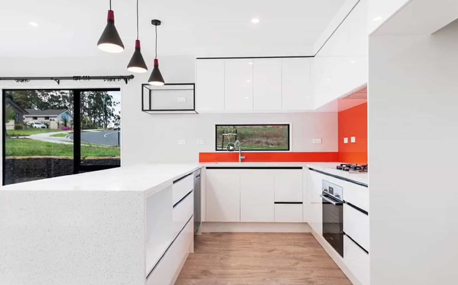 U-shaped kitchen with a red splashback and a window over the bench, Orewa