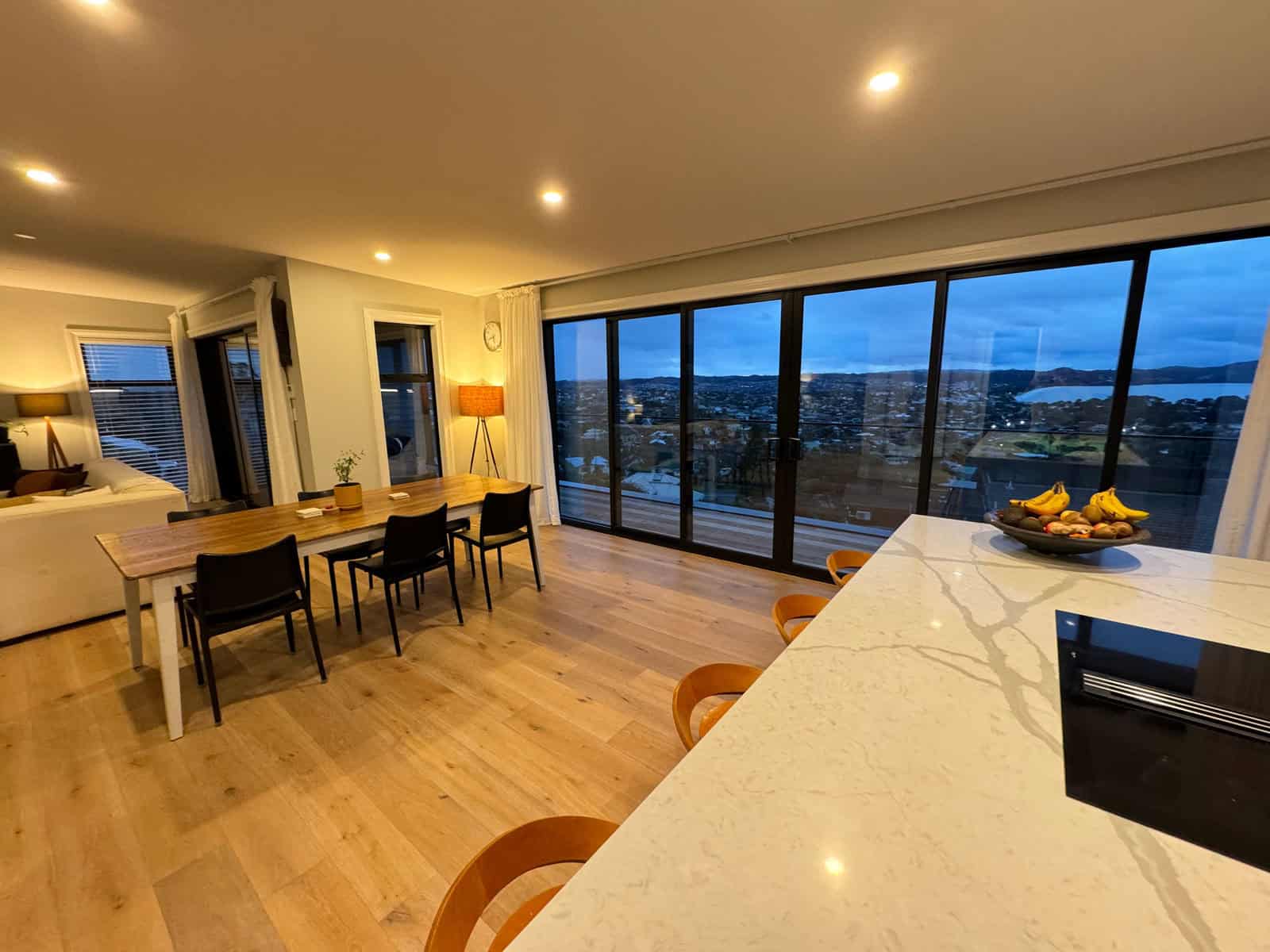 Kitchen island and dining table with the coastal view through full-height glazing, Red Beach