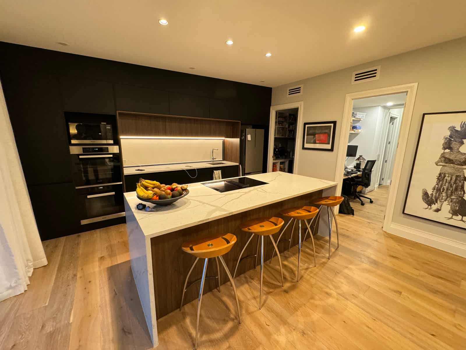 Kitchen with dark cabinetry, a stone island and timber bar stools, Red Beach