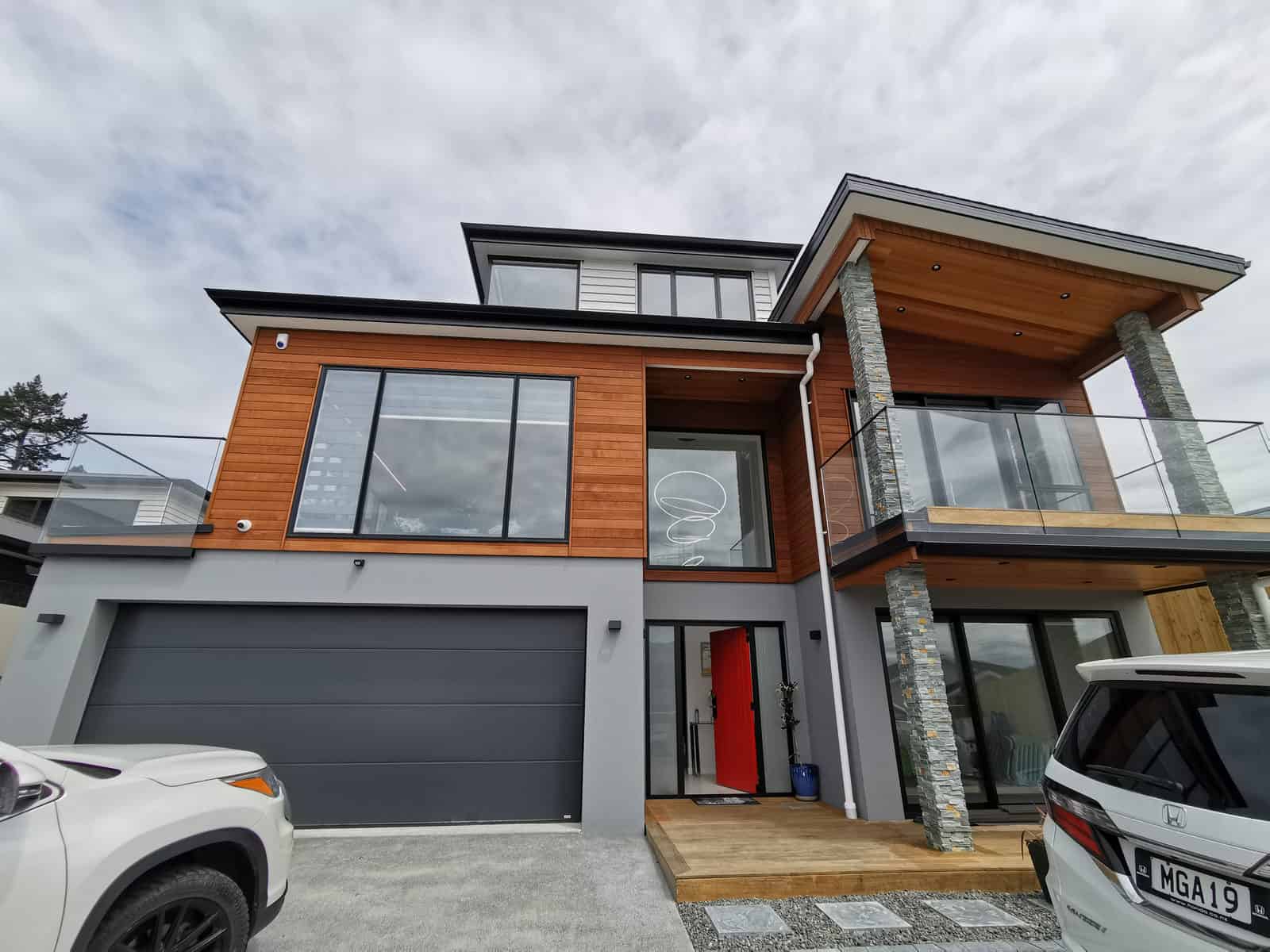 Two-storey house in timber, schist and dark cladding with a double garage, Silverdale