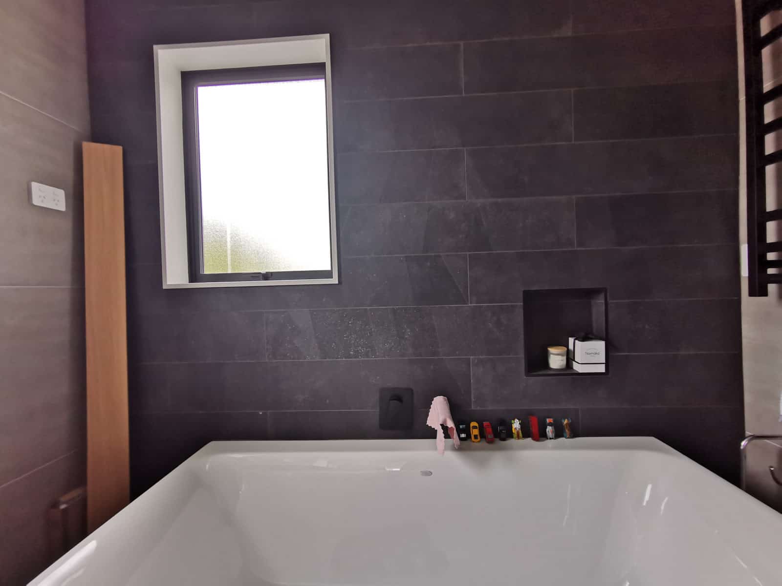 Bathroom with a bath set against dark tiling and a recessed niche, Silverdale