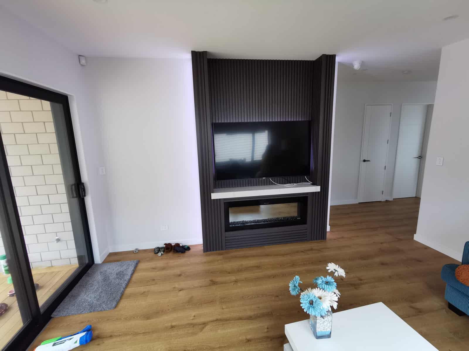 Living room with a gas fire set into a dark battened wall, Silverdale