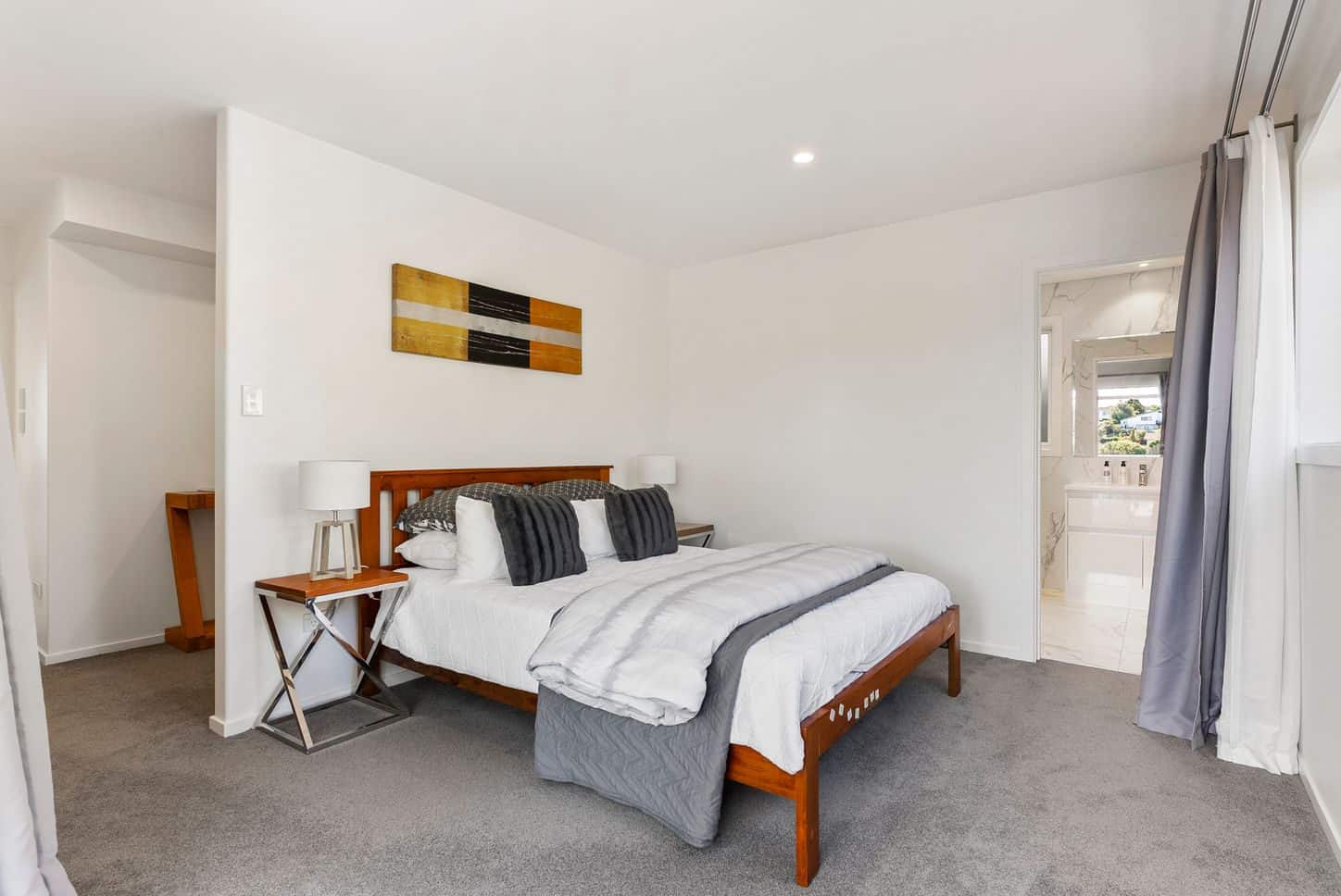 Bedroom with an ensuite through the doorway and a timber bed frame, Sunnynook