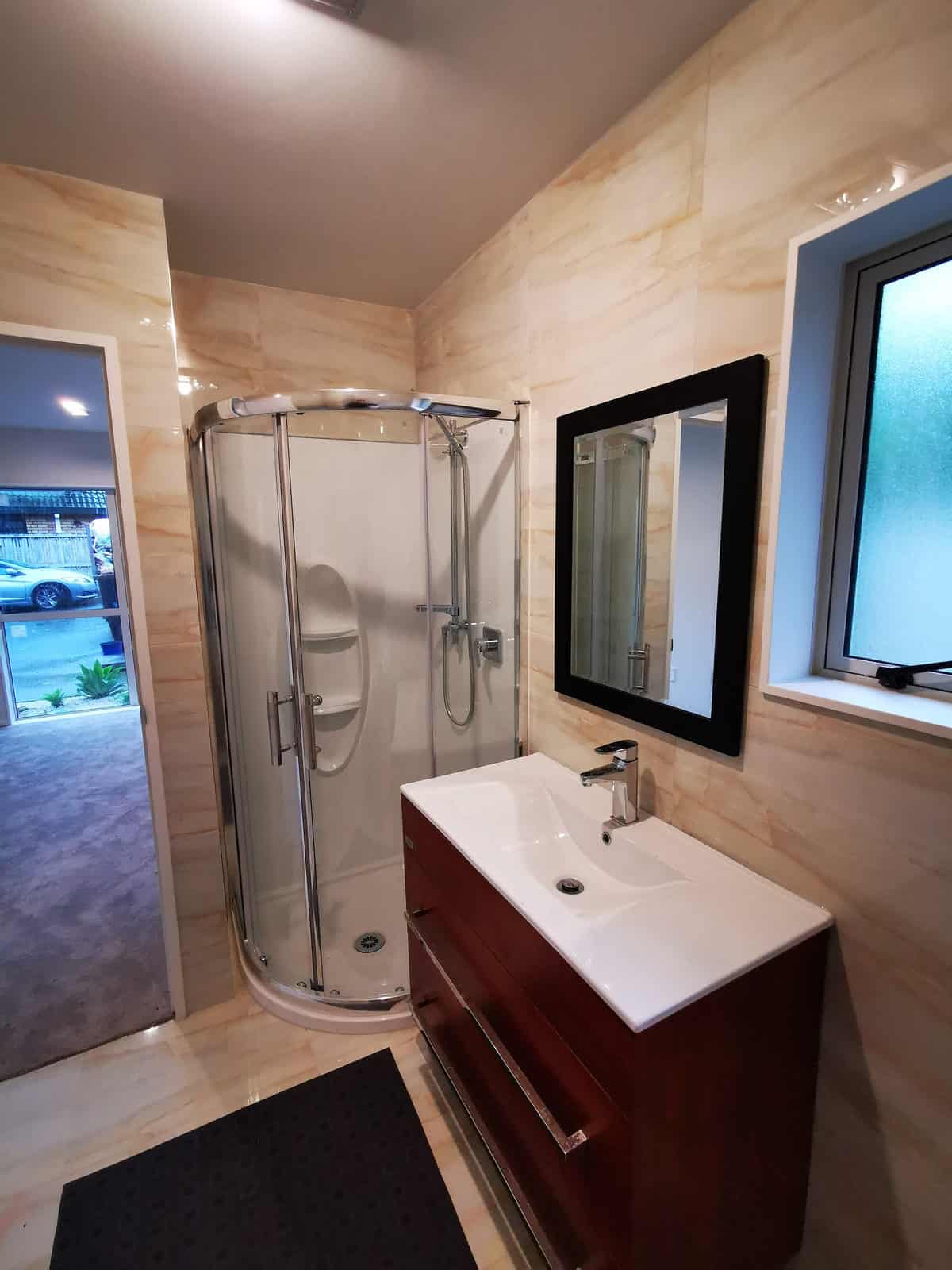Bathroom with a corner shower, timber vanity and a framed mirror, The Gardens
