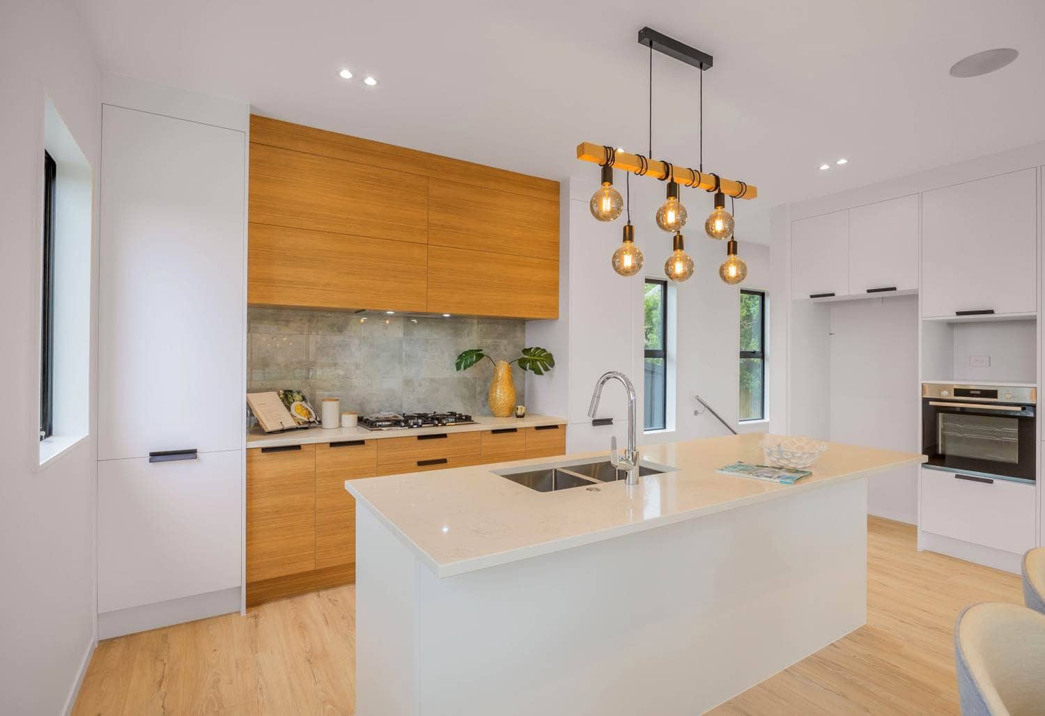 Kitchen with timber cabinetry, a stone island and cluster pendant lights, Torbay