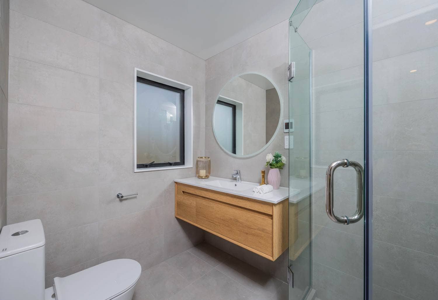 Bathroom with a round mirror, timber vanity and a glazed shower, Torbay