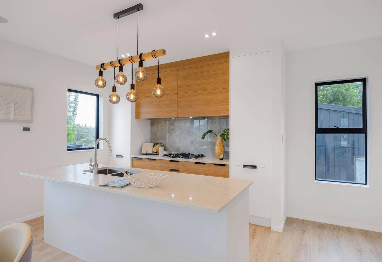 Kitchen with timber overhead cabinetry, a stone island and pendant lights, Torbay