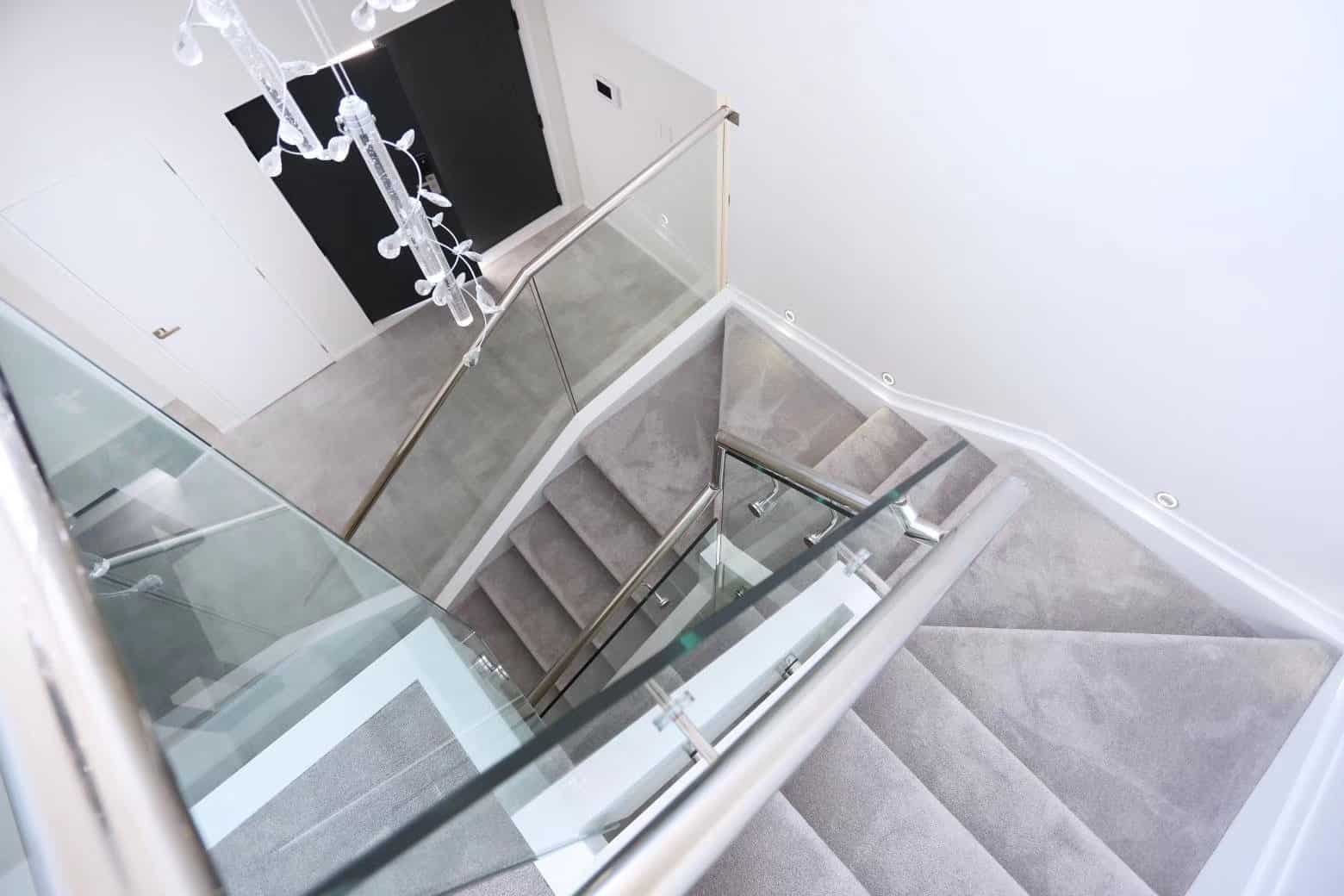Stair with a glass balustrade seen from the landing above, West Harbour