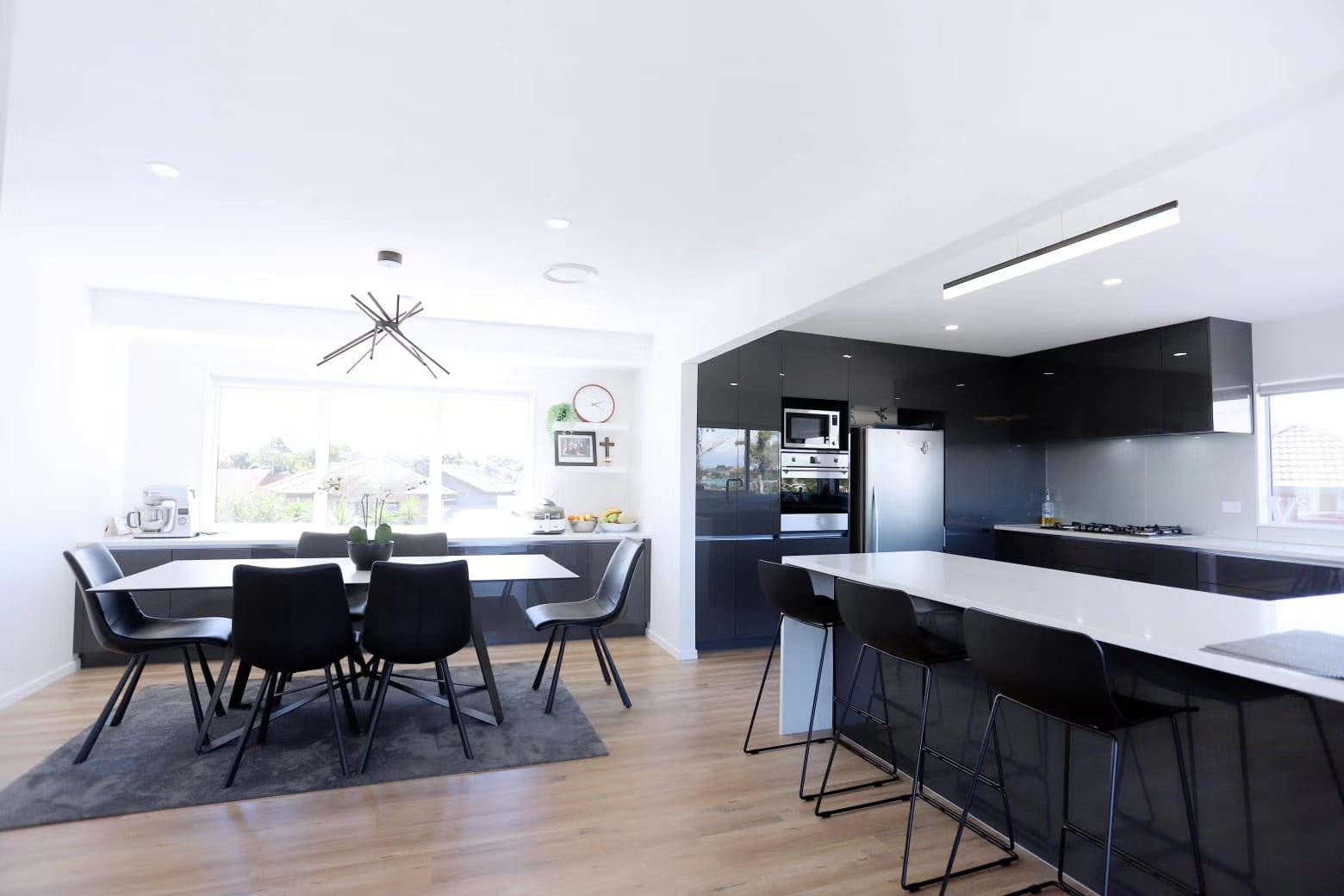 Kitchen and dining with a dark island, bar stools and a linear pendant, West Harbour