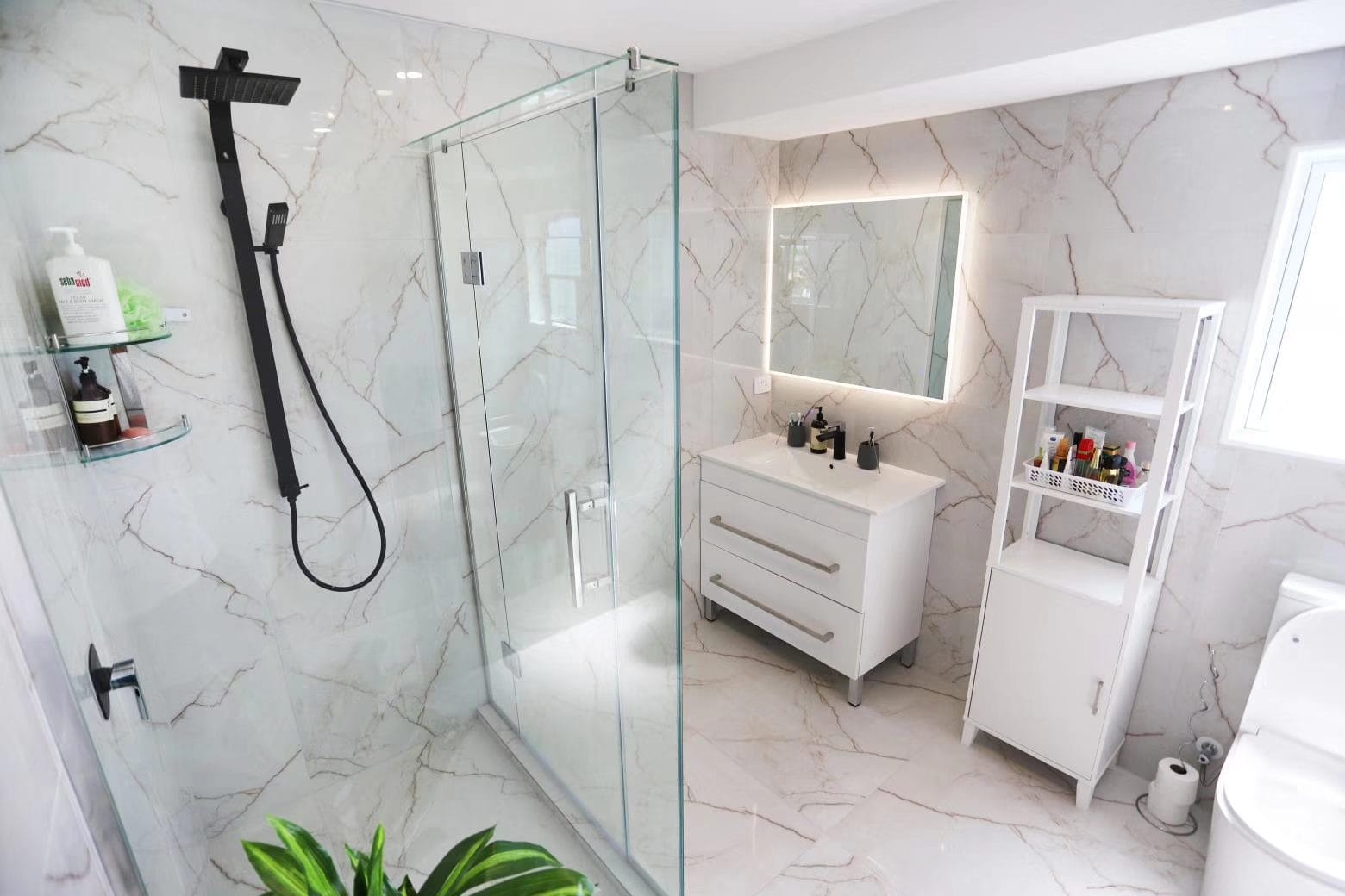 Bathroom with a marble-look tiled shower, backlit mirror and a bath, West Harbour