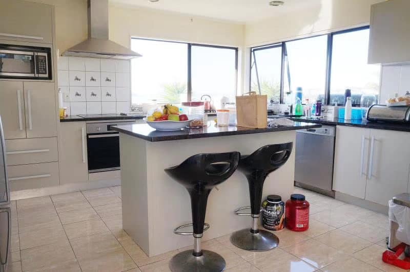 Existing kitchen with a stainless rangehood, island bench and bar stools, West Harbour